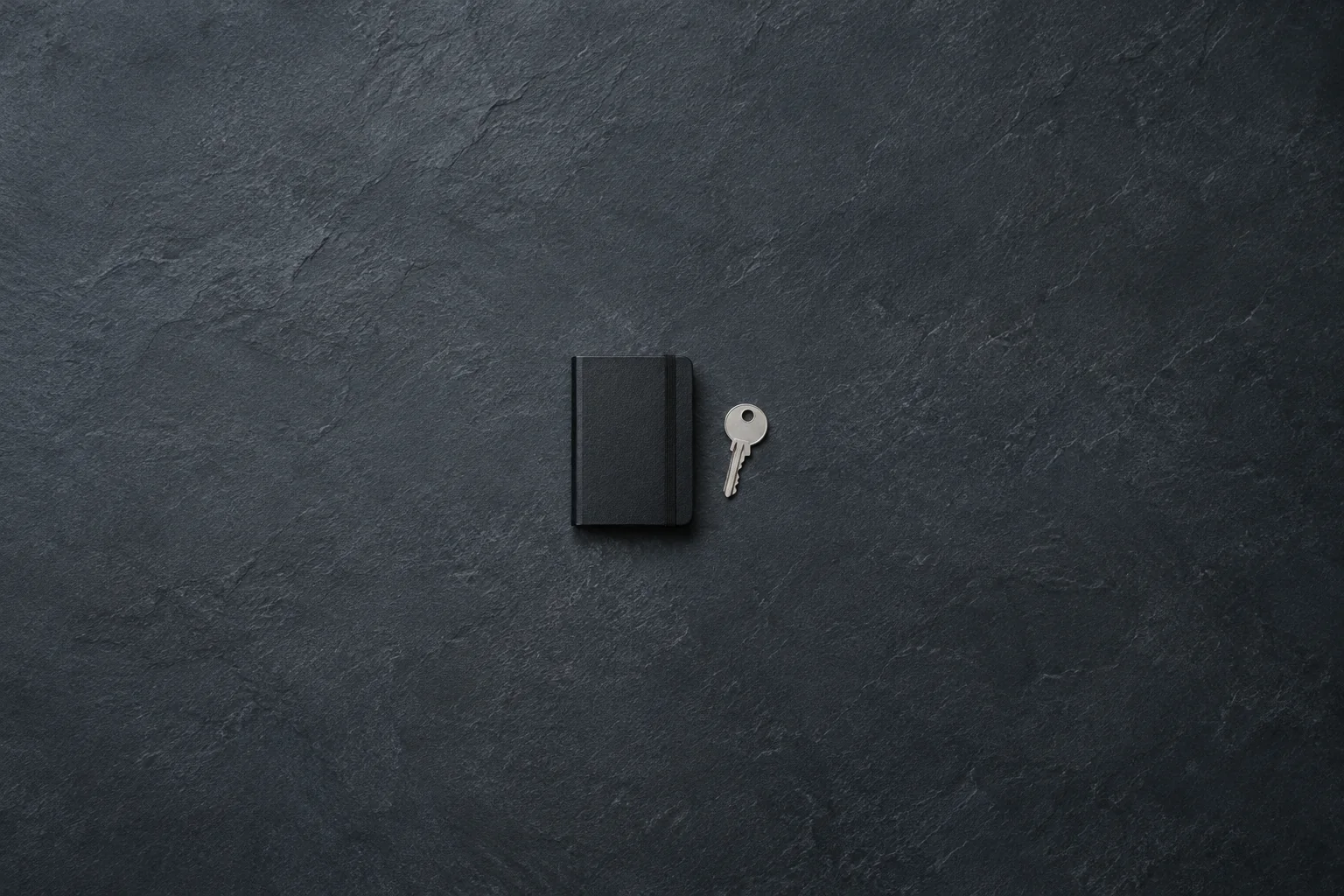 AI-generated editorial illustration of a plain black notebook and loose silver key on a dark slate surface.